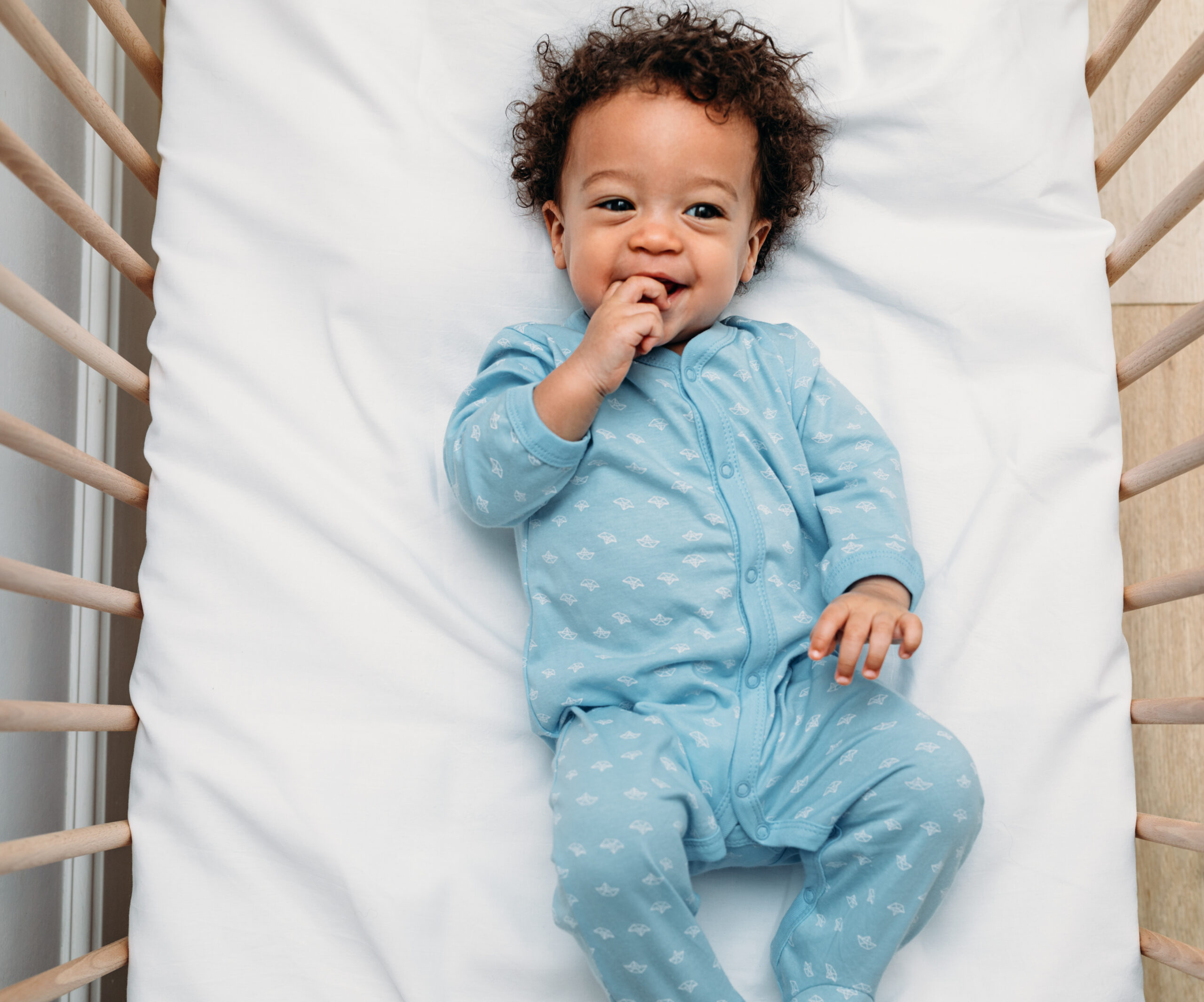 Overhead view of a happy baby boy lying in a crib wearing pajamas Overhead view of a happy baby boy lying in a crib wearing pajamas